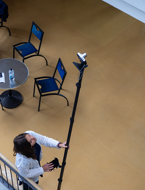 Studierende fotografiert in Galerie mit einem Stativstab