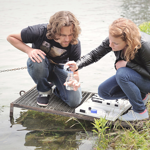 Two students taking water samples from the Rihne river.