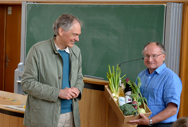 Man sieht die Professoren Nagel und Nägele bei der Überreichung eines Geschenkkorbes