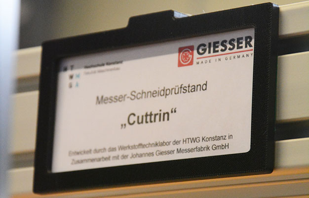 Man sieht das am Prüfstand angebrachte Schild mit der Aufschrift Messer-Schneidprüfstand Cuttrin