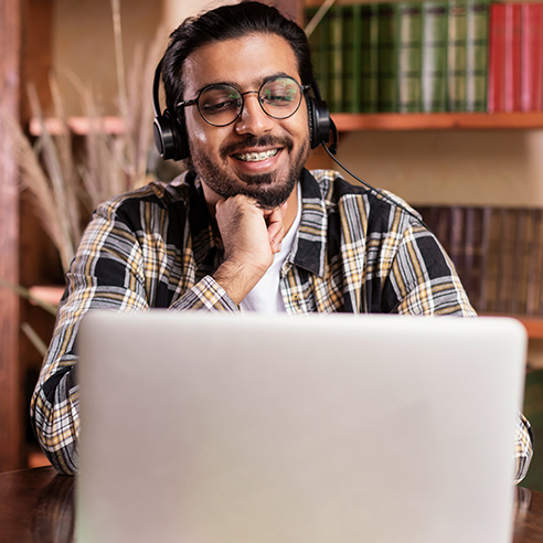 Person with headset looking at their laptop Person with headset looking at their laptop