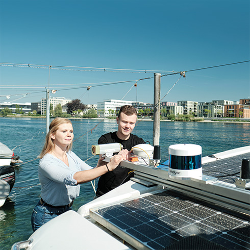 Sustainable Engineering and Future Technologies: Studierende am Solarmodul eines Solarbootes