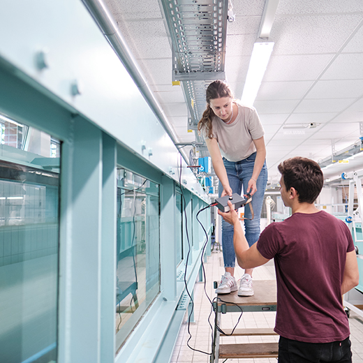 Zwei studierende arbeiten an Kanal im Wasserbaulabor