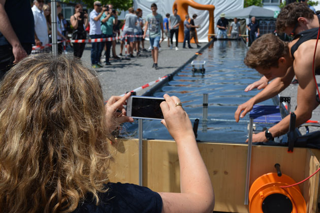 Zu sehen ist der Hinterkopf einer HTWG-Mitarbeiterin, die mit ihrem Smartphone ein Foto von der Renn-Wasserwanne aufnimmt.