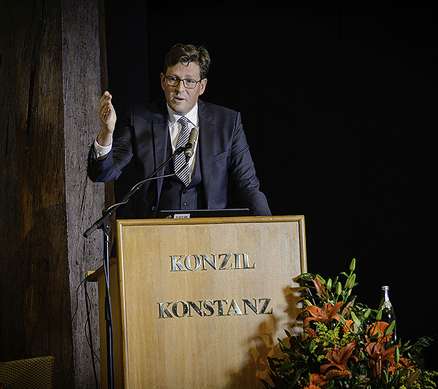 HTWG-Präsident Prof. Dr. Carsten Manz steht am Rednerpult und unterstreicht seine Rede mit einer Geste, indem er die rechte Hand hebt.