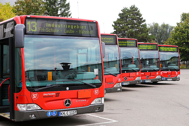 Fünf rote Stadtbusse von vorne, die hintereinander auf dem Parkplatz stehen, so dass jeweils die Windschutzscheibe zu sehen ist