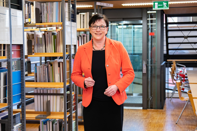 HTWG-Präsidentin Prof. Dr. Sabine Rein steht vor Bücherregalen der Bibliothek.