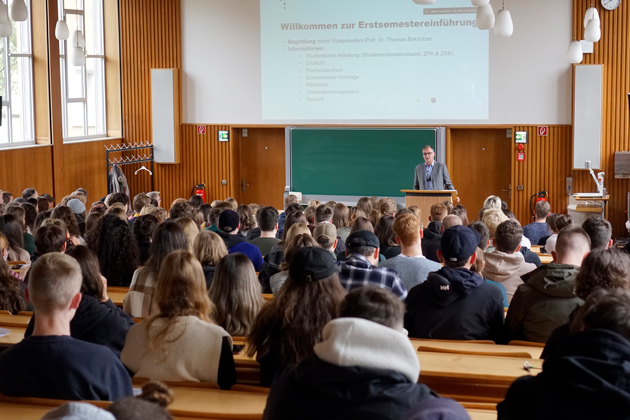 Prof. Dr. Thomas Birkhölzer steht vor einem voll besetzten Hörsaal am Rednerpult.