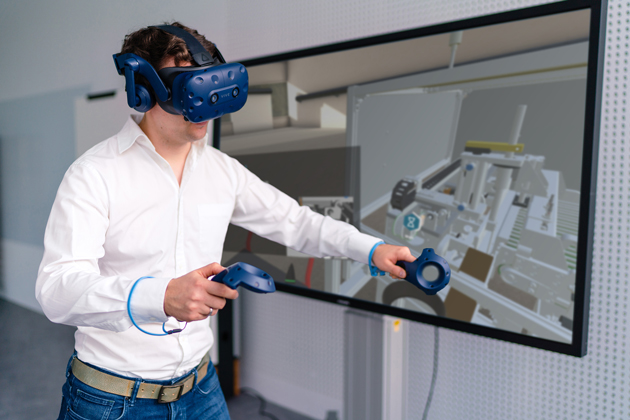 Zu sehen ist ein junger Mann, der eine VR-Brille trägt und mit den Hängen zwei Controller steuert.