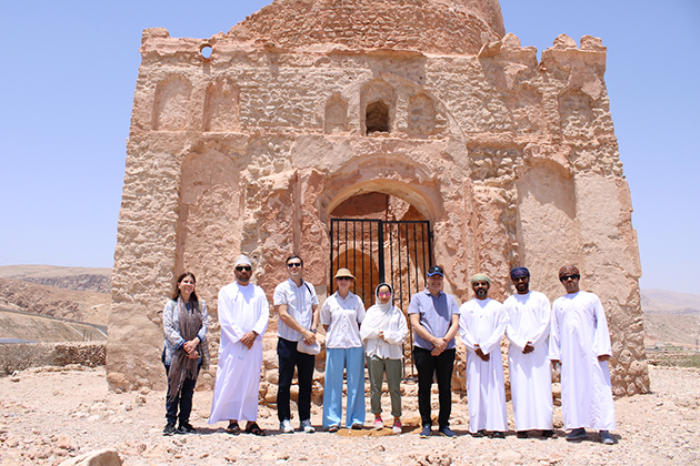 Nachhaltiger Tourismus für UNESCO Weltkulturerbestätten im Oman Das Foto zeigt die 9 Projektteilnehmerinnen und -teilnehmer vor einem Denkmal aus Stein