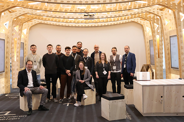 Das Bild zeigt das Team um das Wikihouse Projekt in ihrem selbstgebauten Messestand