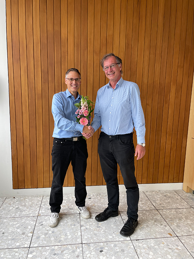 Thomas Birkhölzer überreicht Marcus Kurth einen Blumenstrauß und schüttelt ihm die Hand