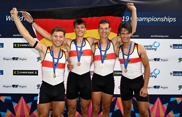 Das Foto zeigt die vier glücklichen Ruderer mit der Deutschlandflagge bei der Siegerehrung