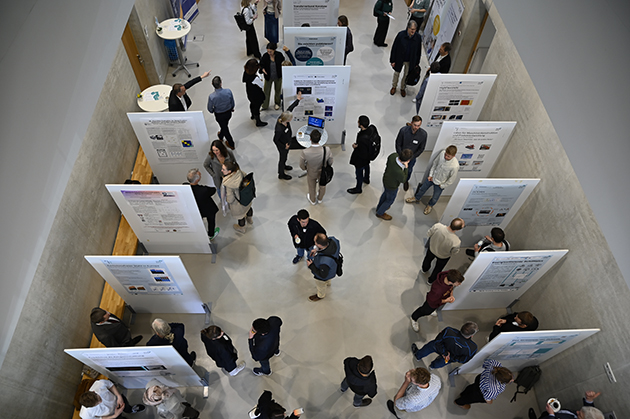 Ein Bild aus der Vogelperspektive aufgenommen zeigt die Posterausstellung und einige Menschen, die sich austauschen.