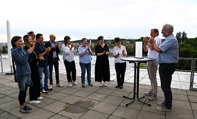 Eine Gruppe Erwachsener freut sich über die symbolische Übergabe des Leitbild Lehre