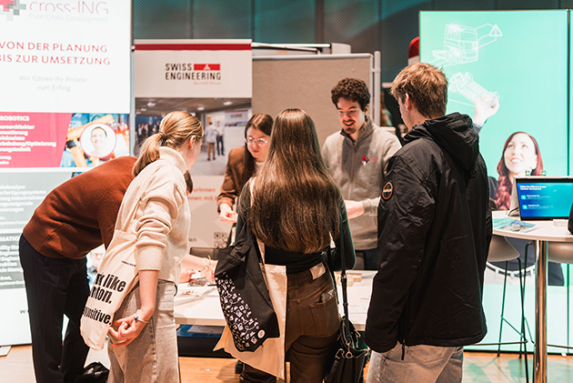 Vier Studierende informieren sich an einem Infostand.