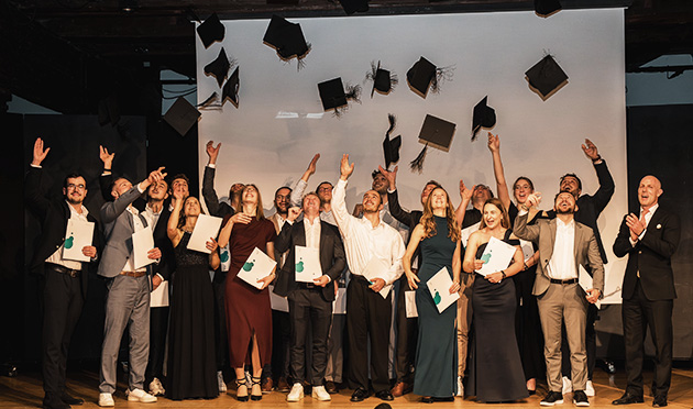 Eine Gruppe Studierender feiert ihren Studienabschluss auf einer Bühne