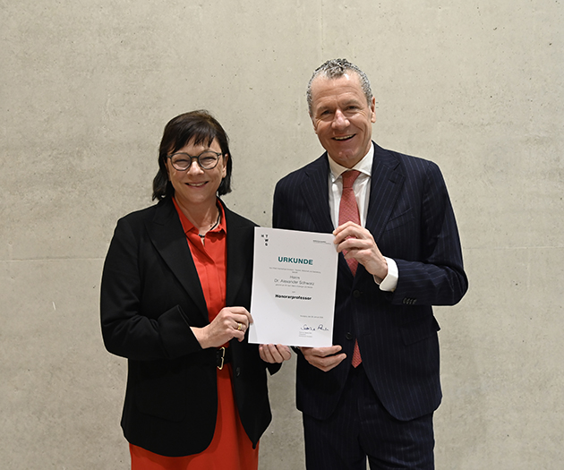 Eine Frau und ein Mann halten feierlich ein Urkundenblatte in der Hand