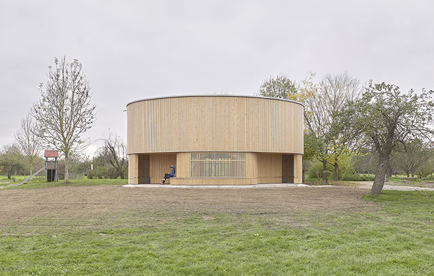 Ein moderner Holzbau steht auf einer grünen Wiese