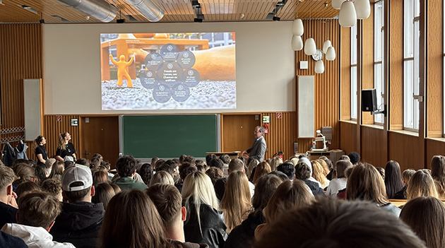 Studierende sitzen in einer Aula und schauen eine Präsentation an