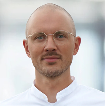 Das Porträtbild zeigt einen Mann mit Brille, der in die Kamera schaut
