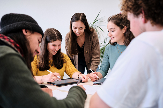 5 Studierende arbeiten an einem Tisch sitzend zusammen