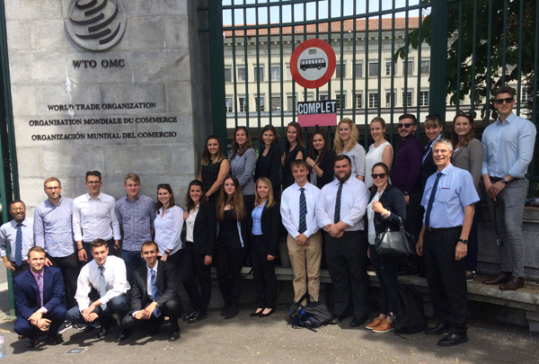 Studierende posieren für ein Gruppenfoto vor dem Eingang des Sitzes der Welthandelsorganisation in Genf. 