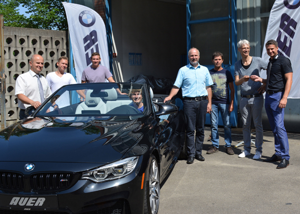 Eine Gruppe Menschen steht zum Gruppenfoto um ein BMW-Cabrio herum.