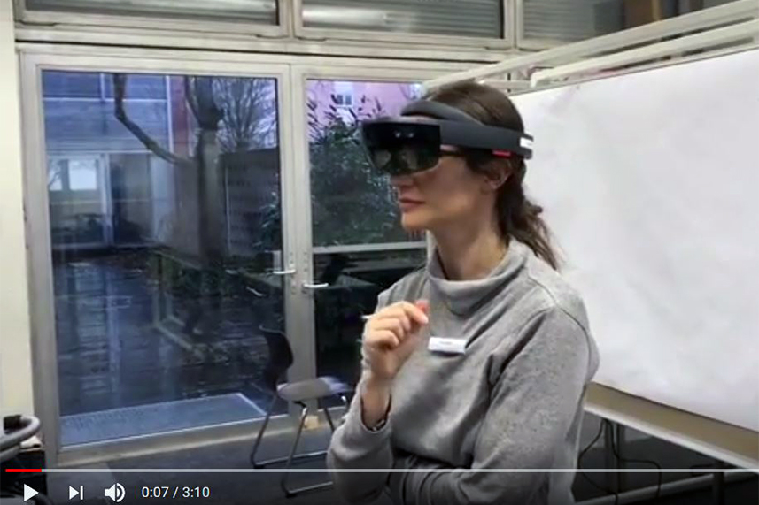 Ein Screenshot des Videos über den Hololens Hackathon: Eine Frau trägt eine VR-Brille.