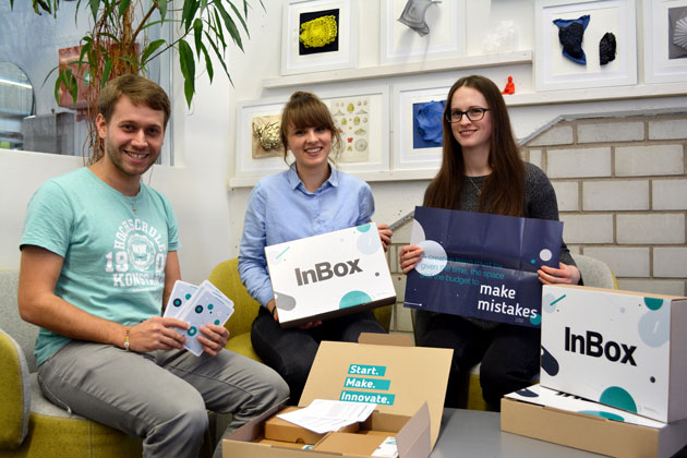 Christoph Selig, Startup-Beauftragter der HTWG, Sophie Mehlhart (Mitte) und Melanie Fischer (rechts) sitzen im Kreis auf Sesseln. Sie halten Teile der Box in den Händen. Auf einem Tisch vor ihnen steht die Box.