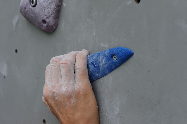 Eine Hand, die einen Klettergriff greift, in Großaufnahme.