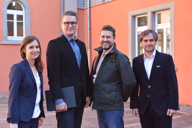 Doktorandin Lena Pauli, Prof. Dr. Hans-Peter Schelkle, Tim Whitehill von Project 5 aus England und Prof. Dr. Andreas Großmann posieren für ein Gruppenfoto vor einem Gebäude auf dem HTWG Campus.