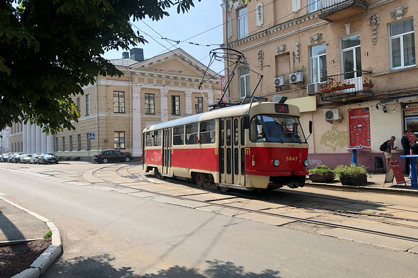 Blick auf einen roten Trolleybus, der in einer Straße einer osteuropäischen Stadt vor einem Inbiss steht..