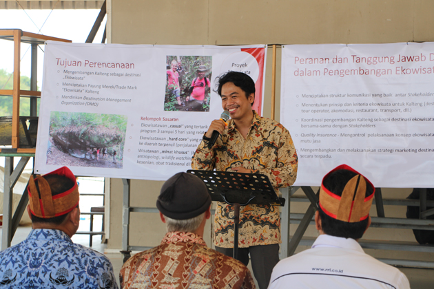 Der Indonesier Dwi Novaldi steht mit einem Mikrofon in der rechten Hand vor einem sitzenden Publikum. Hinter ihm hängen weiße Plakate mit schwarzer Schrift.