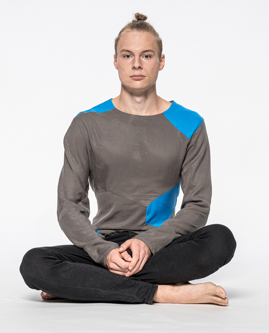 Ein Mann im Schneidersitz präsentiert ein langärmeliges T-Shirt.