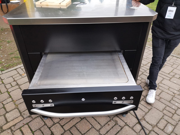 Aus der Vogelperspektive ist wie eine ausgefahren Schublade aus einer schwarzen Kommode eine Grillplatte zu sehen.