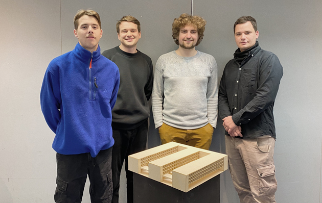 Gruppenaufnahme des Gewinner-Teams der HTWG. Im Vordergrund steht auf Hüfthöhe das Holzmodell eines Architekturentwurfs. Von links nach rechts: Jan Schreiber, Adrian Stibi, Felix Daumüller und Dominik Pelz.