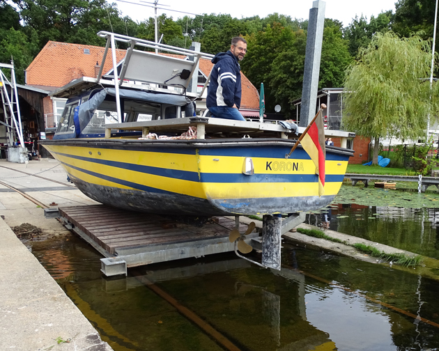 Laboringenieur Peter Rasch kniet auf dem Boot, das auf einer Slipanlage in den Tegeler See gelassen wird.