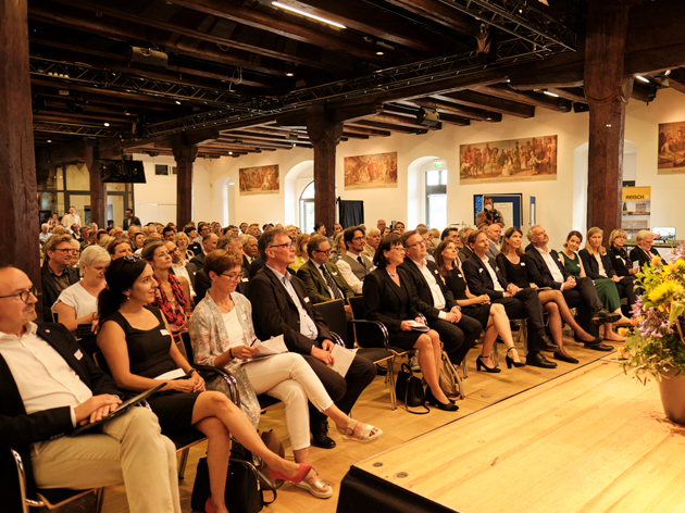 Blick in einen Saal mit Publikum in Kinobestuhlung