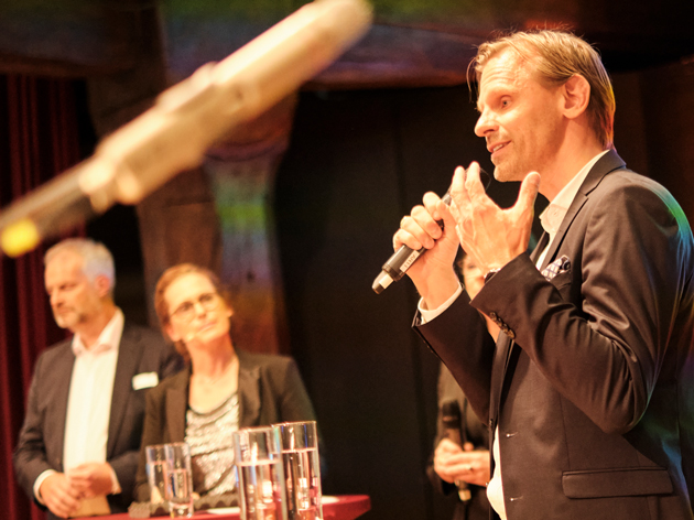Prof. Dr. Gunnar Schubert mit Mikrofon in der Hand auf der Bühne