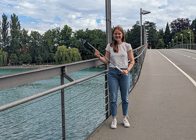 HTWG-Konstanz-Bauingenieurwesen-Studium-Studentin-Fahrradbrücke Eine Bauingenieurwesen-Studentin steht auf einer Brücke und hält einen Meterstab in der Hand.