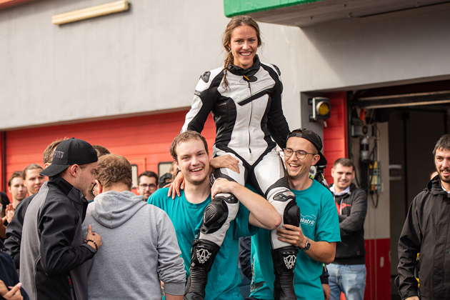 Maschinenbau-Studentin Hannah Schienle sitzt in Motorradkluft auf den Schultern von zwei Mitgliedern des Teams eLaketrik.