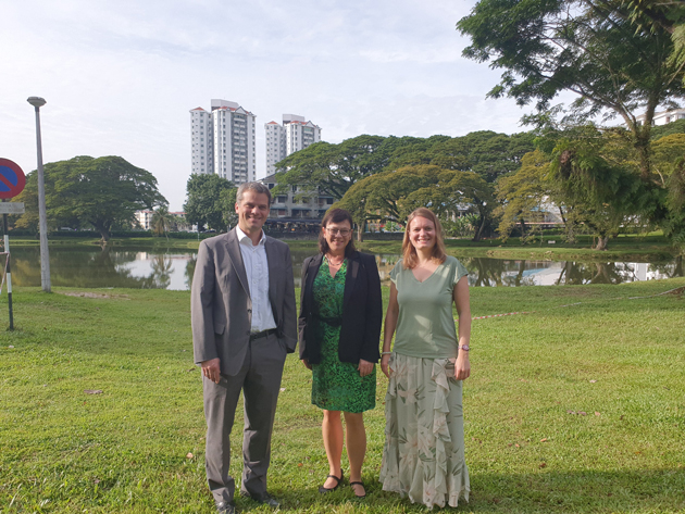 Gruppenfoto mit drei Personen auf einer grünenn Wiese, im Hintergrund drei Hochhäuser. Vorne stehen von links: Verena Gründler, Prof. Dr. Sabine Rein und Prof. Dr. Heiko Denk.