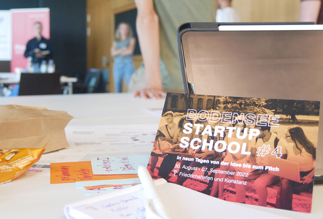 Auf einem Tisch steht eine Karte mit der Aufschrift "Startup School".