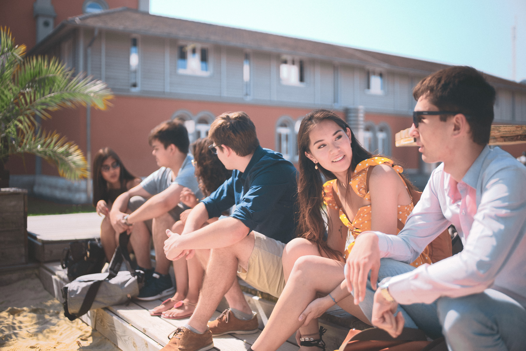 Eine Gruppe Studierender sitzen in der Sonne an der Strandbar