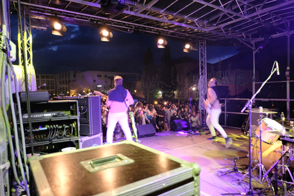Die dreiköpfige Band "Reiche Söhne" spielt auf der beleuchteten Bühne auf dem Sommerfest der HTWG im Sommer 2019