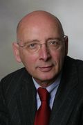 Josef Wieland mit Glatze, dunklen Anzug und roter Krawatte.