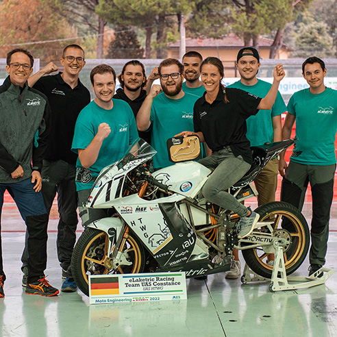 Gruppenfoto eines Teams aus Studierenden, vorne ein weißes Motorrad