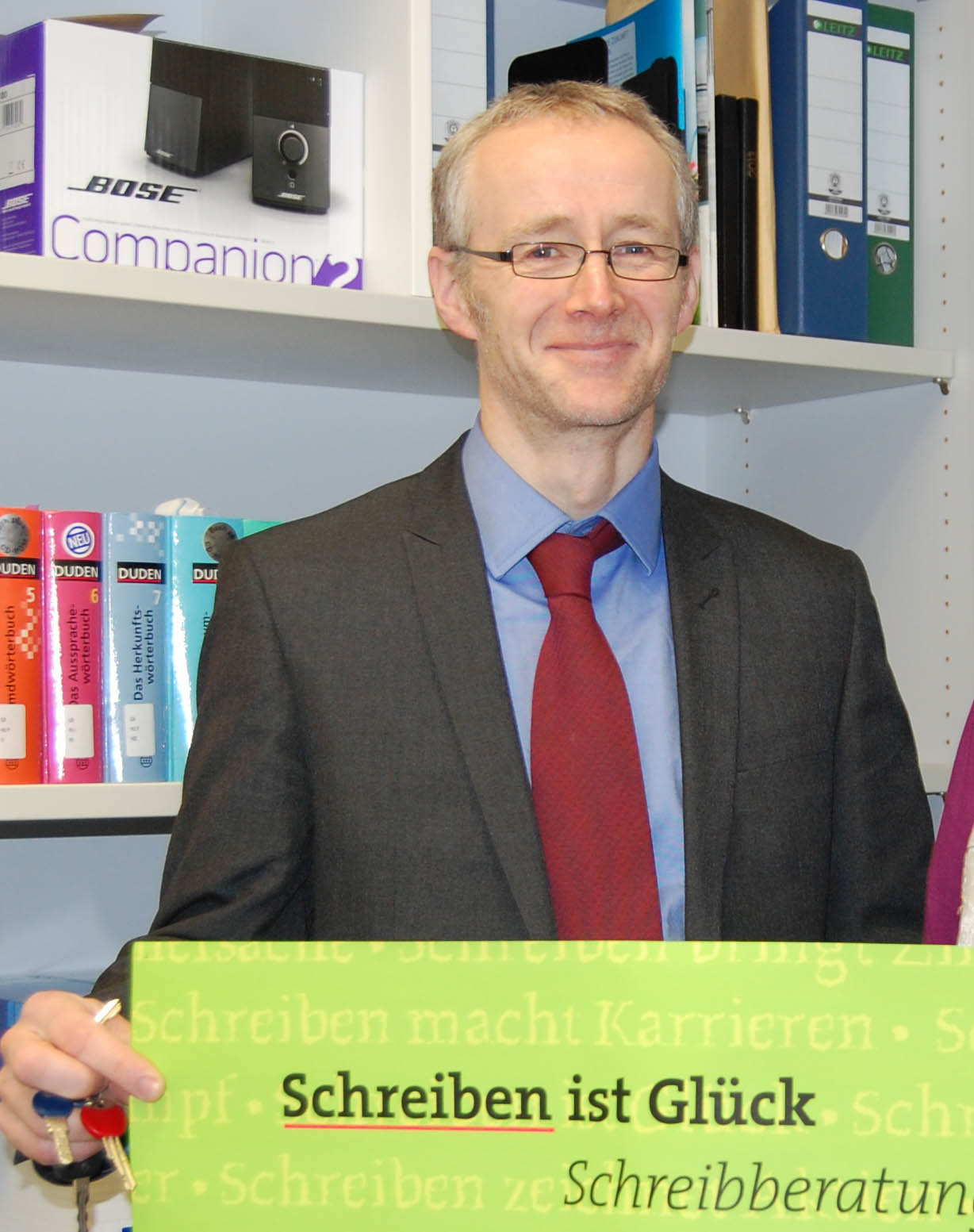 Porträtbild Prof. Christian Krekeler mit Plakat der Schreibberatung