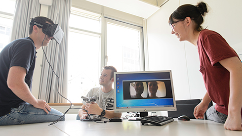 Studierende mit VR-Brille und Monitor